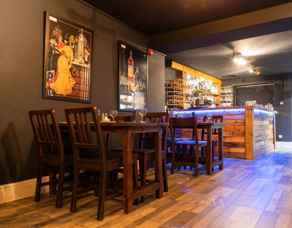 Restaurant tables beside a timber-clad bar with blue under-lighting and vintage posters, the Log Room at the Feversham Arms, Helmsley