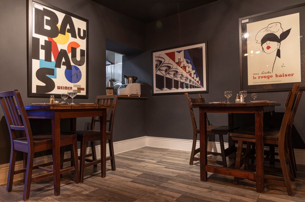 Dining tables under framed Bauhaus and vintage posters on charcoal walls, the Log Room at the Feversham Arms, Helmsley