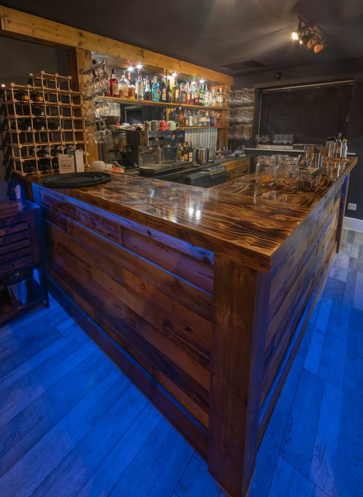 Reclaimed timber bar with glass shelving and blue LED floor lighting, the Log Room at the Feversham Arms, Helmsley