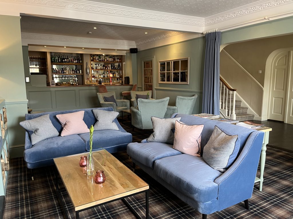 The Log Room in Helmsley: blue velvet sofas and pink cushions in front of the bar