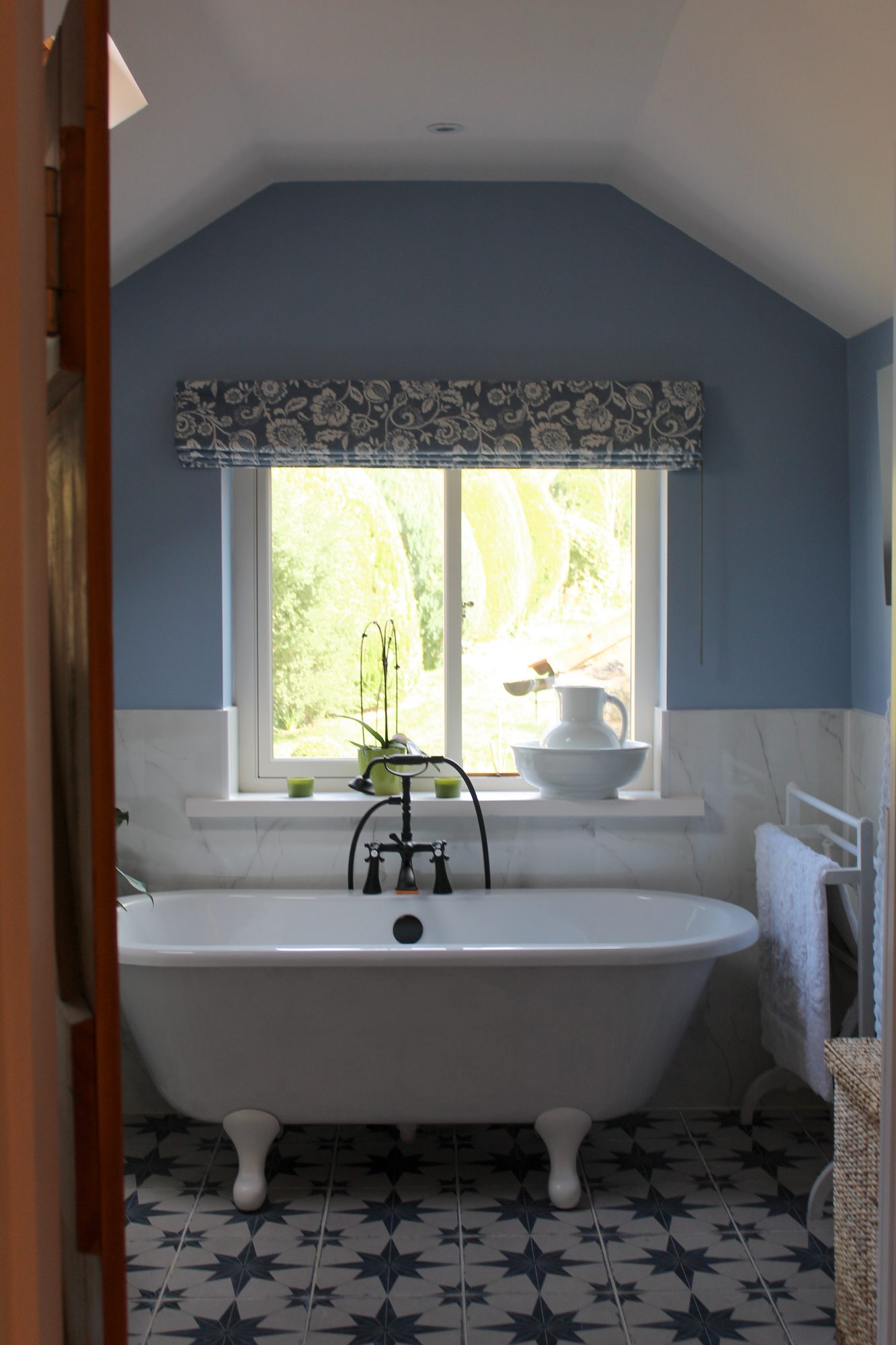 Cottage bathroom with roll-top bath and William Morris style patterned blind
